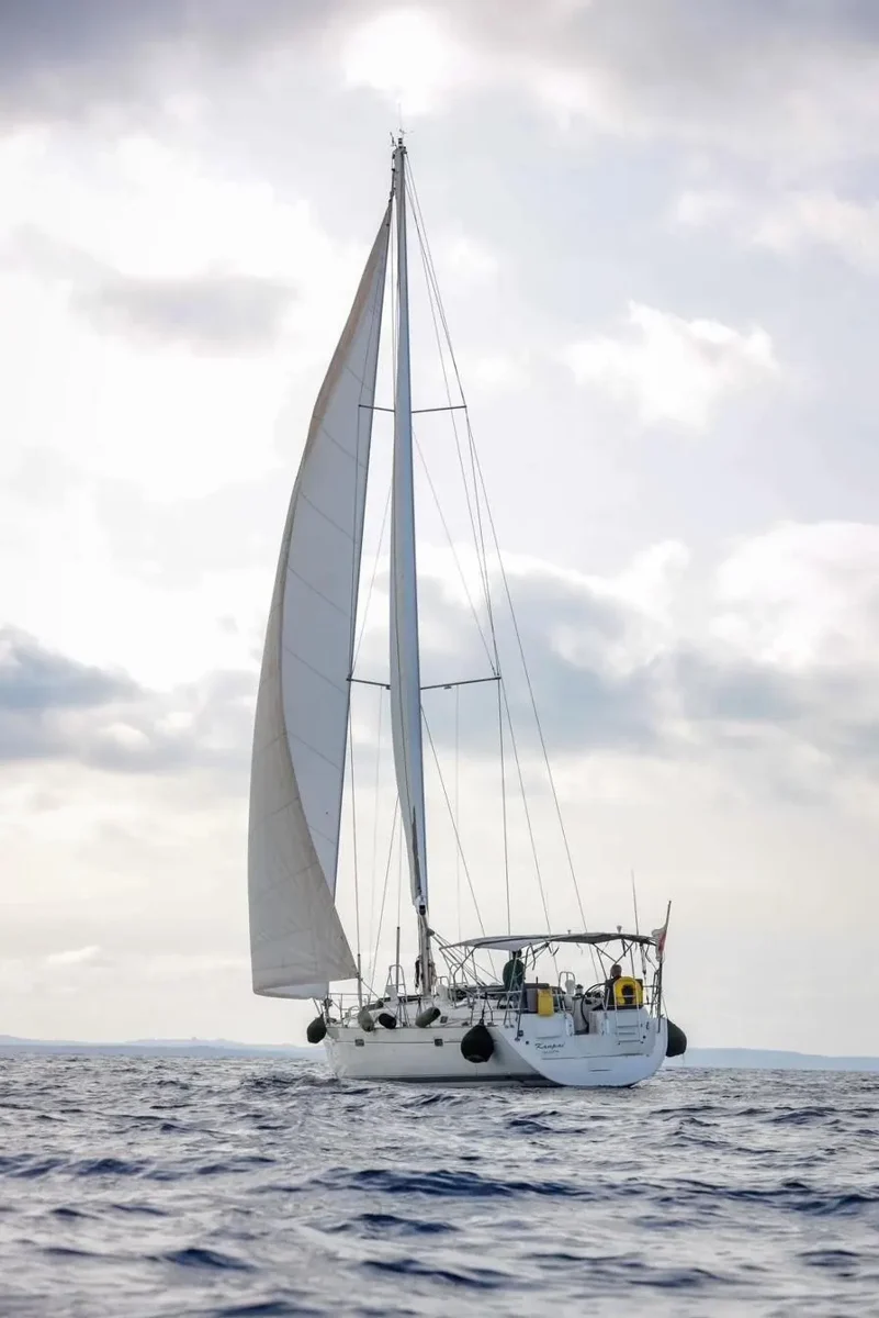 Beneteau 50 sailing with white sails against a bright sky